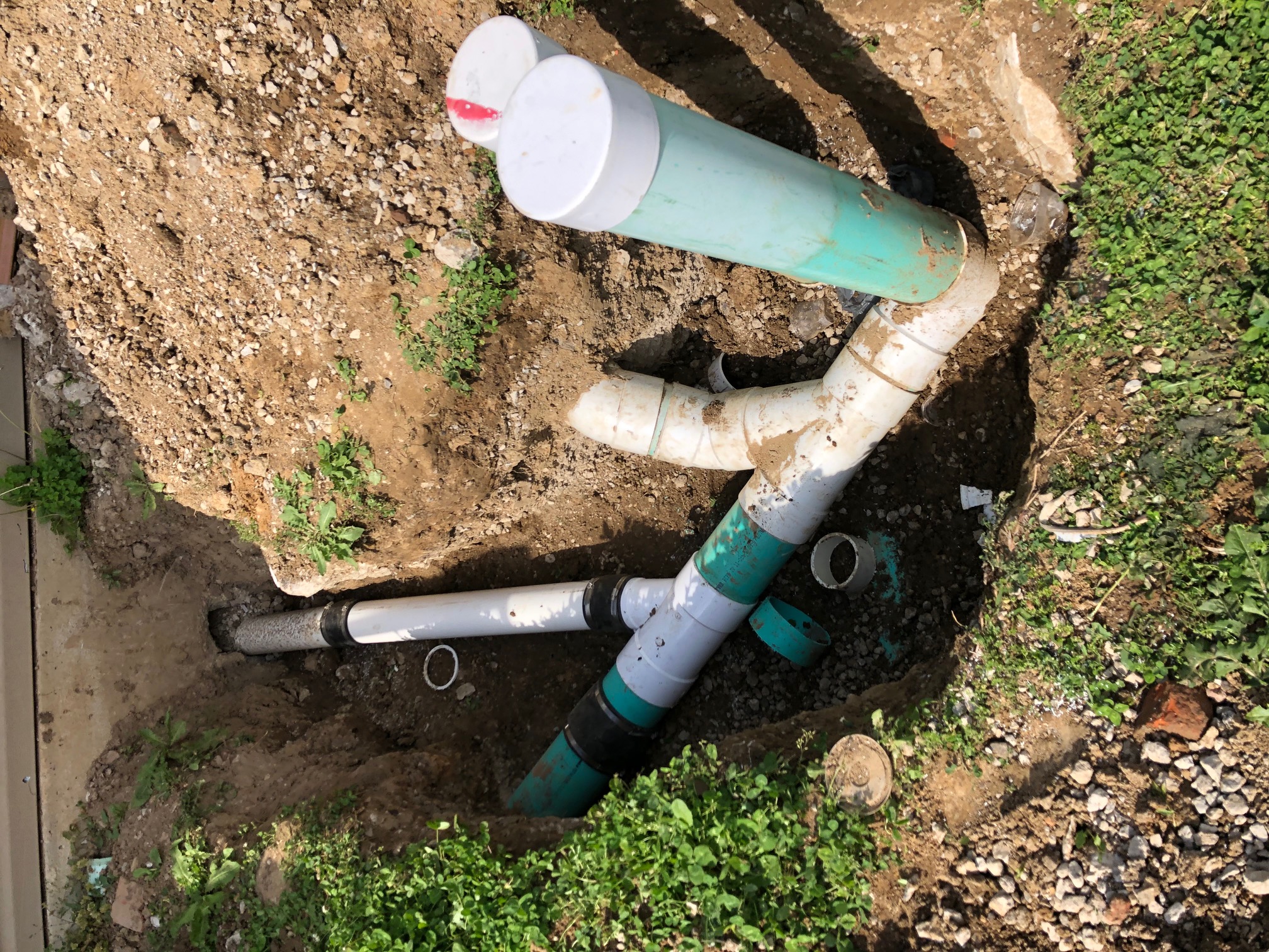 Outdoor sewer pipe connections and capped cleanouts in an open excavation