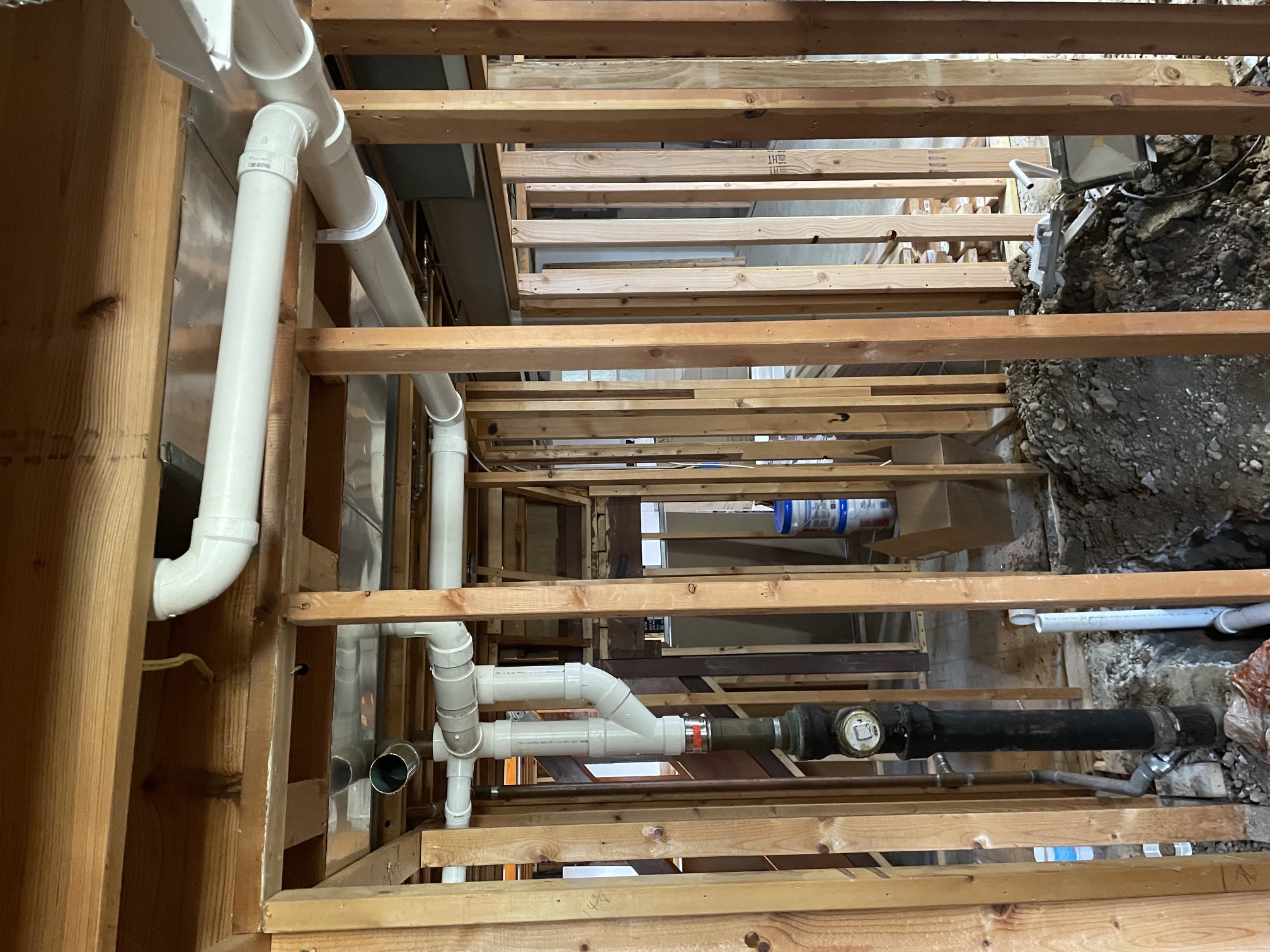 White plumbing pipes within exposed wall framing during renovation