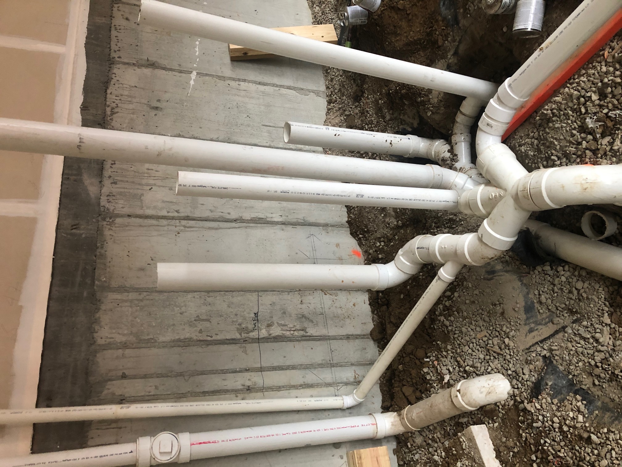 Drain rough-in with upright pipes and connections in a gravel floor